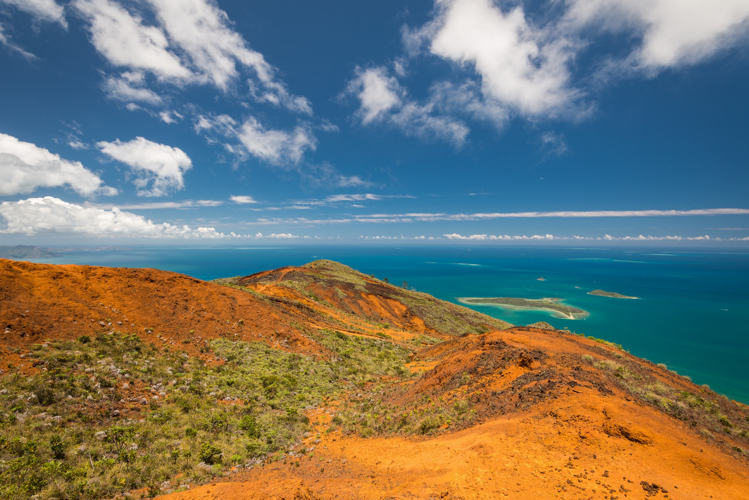 Paysage naturel avec une colline verdoyante, un plan d’eau calme et un ciel bleu clair - randonnée et nature avec Aktiv Trek